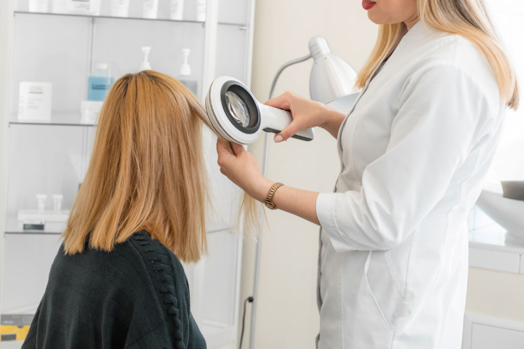 A Trichologist examining long hair using a scalp magnifying glass